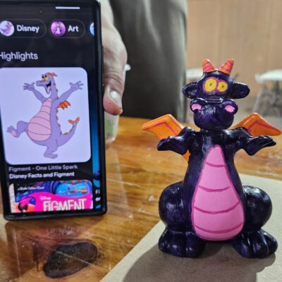 Hand-painted Figment Disney character figurine next to a phone displaying Figment art.