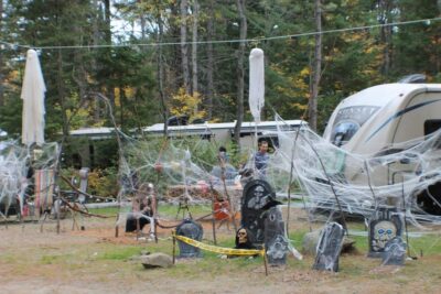 Spooky Halloween decorations with ghosts, tombstones, and cobwebs at a campsite.