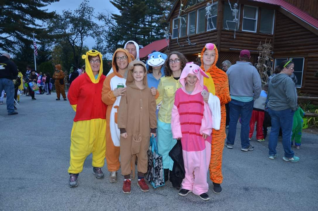 Group of people in Winnie the Pooh, Piglet, Tiger, and other animal onesie costumes.