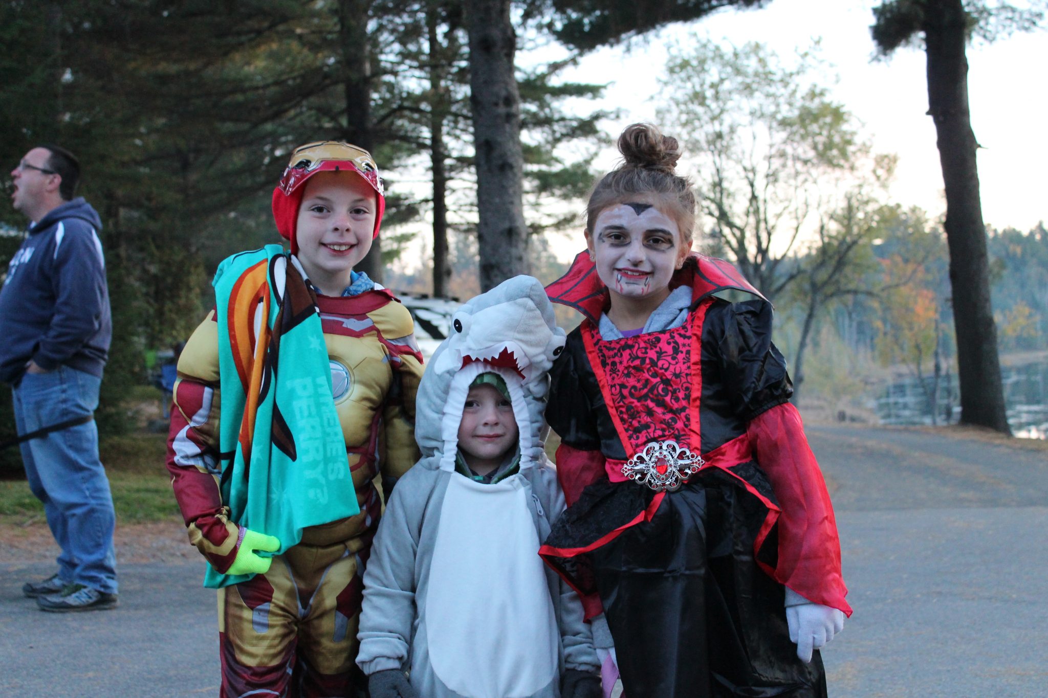 Kids in Halloween costumes: Iron Man, shark, and vampire.