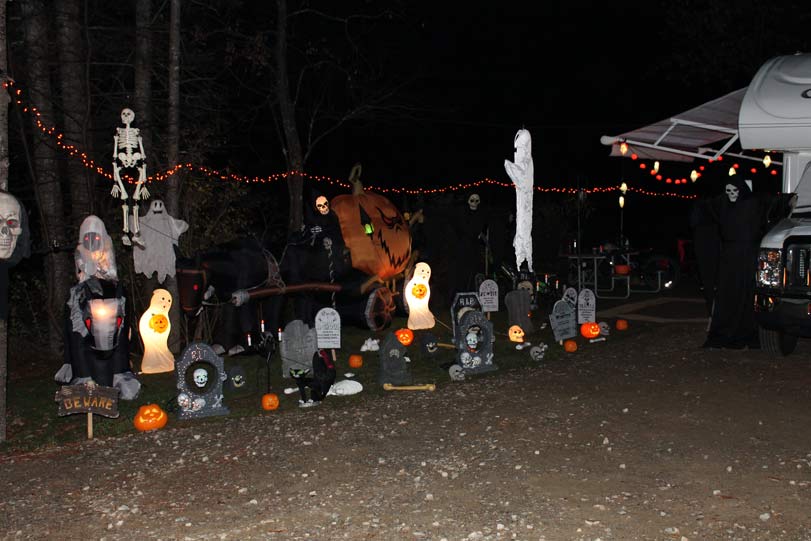 Spooky Halloween campsite decorations with skeletons, ghosts, pumpkins, and tombstones.