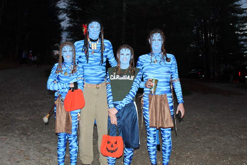 Family dressed as Na'vi from Avatar for Halloween, holding pumpkin buckets.