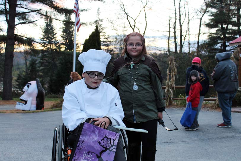 Kids in Halloween costumes, one in chef outfit in wheelchair, other as archer.