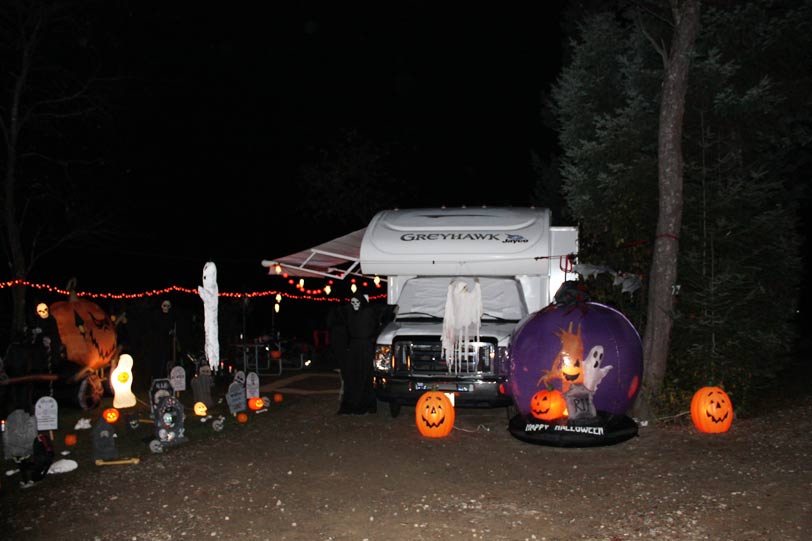 RV decorated for Halloween with pumpkins, ghosts, and tombstones.