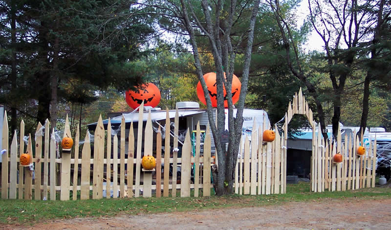 Halloween decorations: inflatable pumpkins, picket fence, carved pumpkins, and spiderwebs.